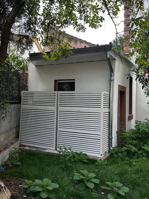 Unité extérieure de la pompe à chaleur, derrière un habillage à lames — immeuble de 5 logements, Strasbourg